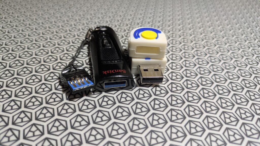 Foto von USB Sticks auf einer Unterlage: links 2x USB-3 und rechts 1x USB-2